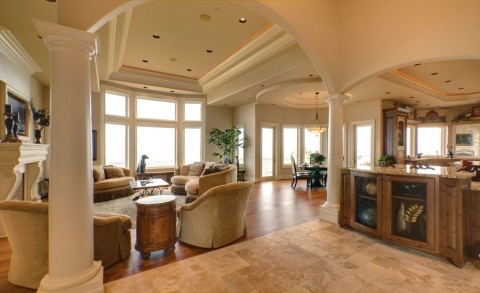An open concept living room with kitchen, sofas, dining room table, and hidden speakers in the ceiling. 