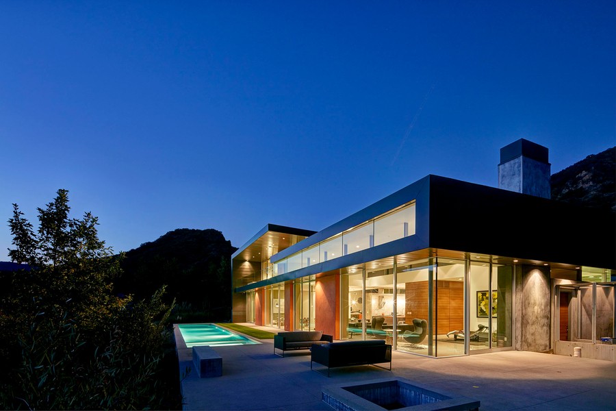 a luxury home with glass windows and a pool lit with LED lighting 