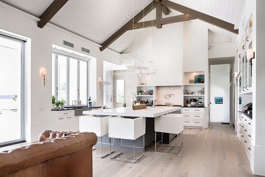 a living room next to a kitchen with a white dining table and chairs in the middle