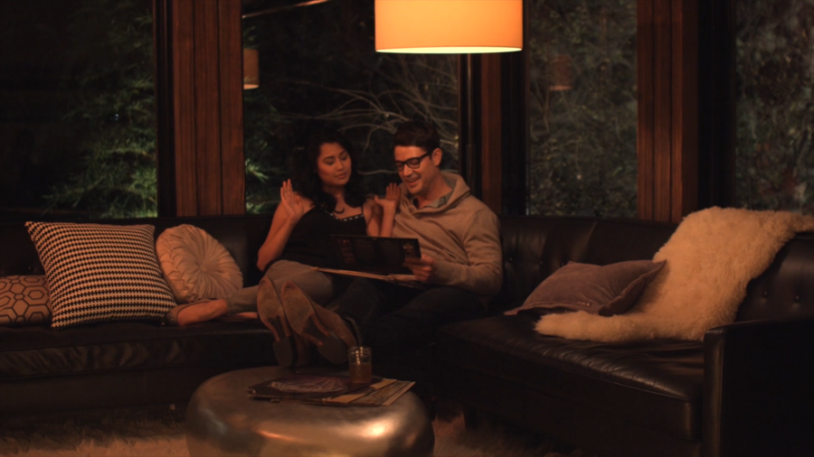 a couple sitting on a couch in a living room with dimmed yellow lights.