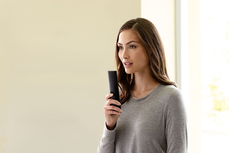 a woman using the voice command feature on a Savant remote.