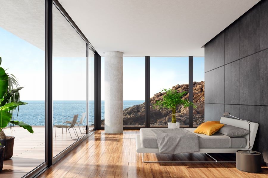 A bedroom with Sonance invisible speakers and picture windows looking out on the ocean.