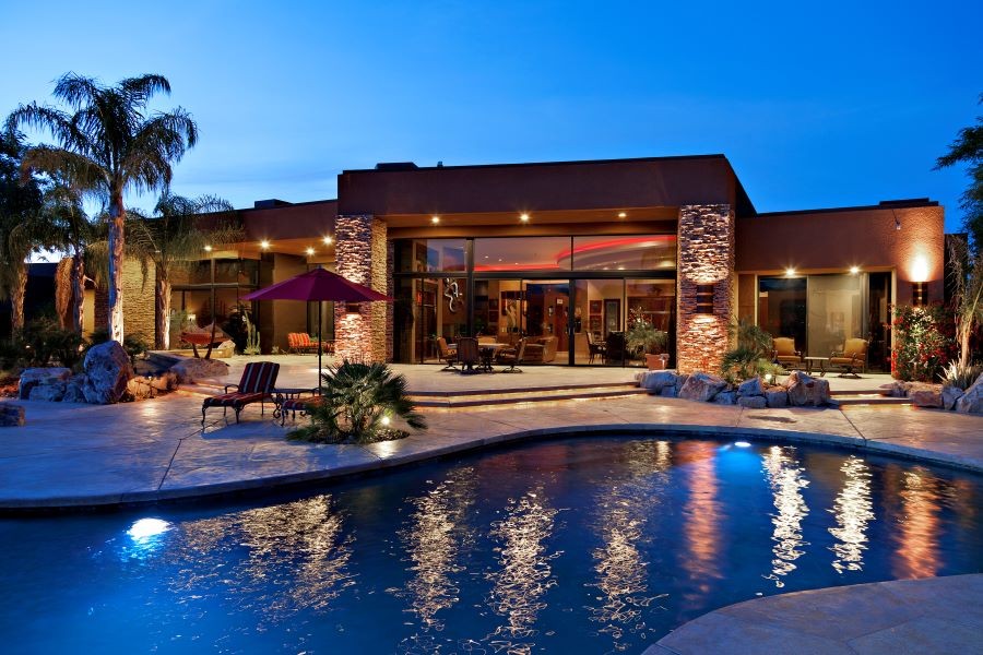 A beautifully lit home with a pool and palm trees in the backyard. 