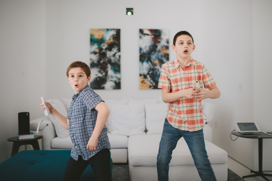 Two kids playing video games enjoying strong home wi-fi connectivity.