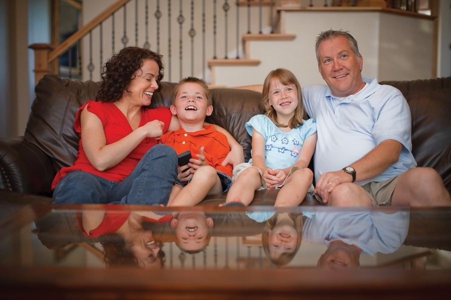 A family enjoys entertainment while sitting on a couch.