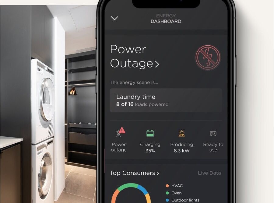 Smartphone displaying an energy dashboard highlighting a power outage scenario, with real-time data on power usage and solar energy production, set beside a modern laundry area with a stacked washer and dryer.